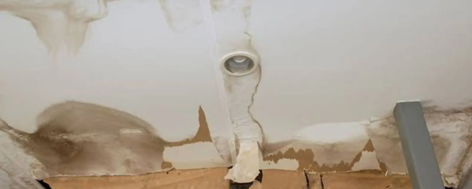 Ceiling with a brown water stain and a damaged section opened up