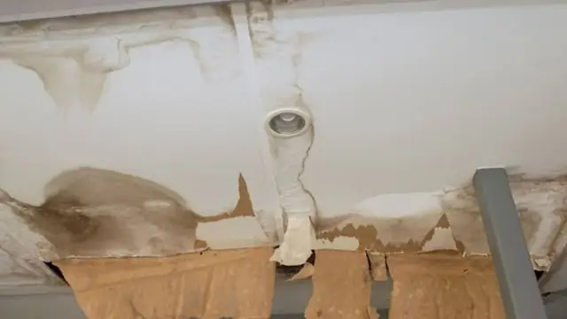 Ceiling with a brown water stain and a damaged section opened up