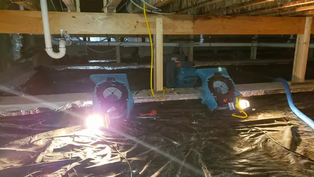 Fans running under a house in a crawl space lined with plastic sheeting